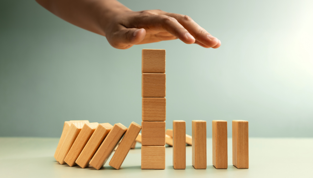 Main arrêtant une chute de dominos en bois